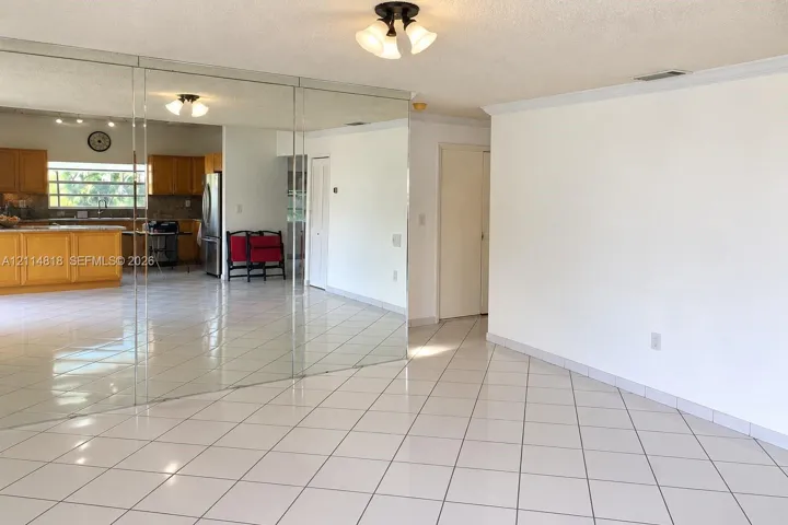Living area featuring large-format ceramic tile flooring, full-height mirrored wall paneling, and a semi-flush mount ceiling fixture