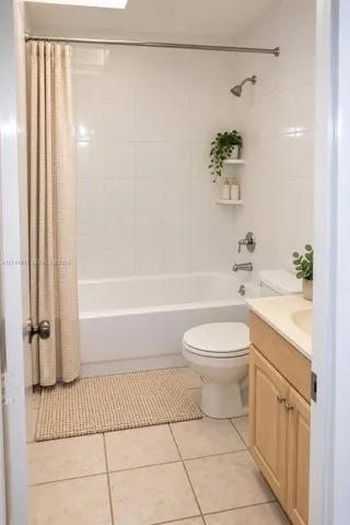 Full bathroom featuring a tub-shower combination with white wall tile, wood-finish vanity cabinetry, a solid surface countertop with integrated basin, and neutral ceramic tile flooring