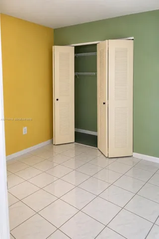 Square tile flooring and closet featuring bifold louvered doors with interior wire shelving
