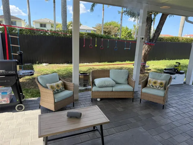 Covered patio featuring paver flooring, white support pillars, and a fenced backyard