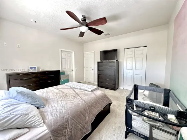 Room featuring neutral wall tones, wall-to-wall carpeting, ceiling-mounted paddle fan with integrated lighting, and dual-panel closet doors
