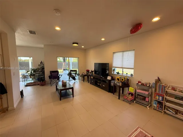 Open-concept living space featuring large-format tile flooring, recessed lighting, and sliding glass doors providing outdoor access