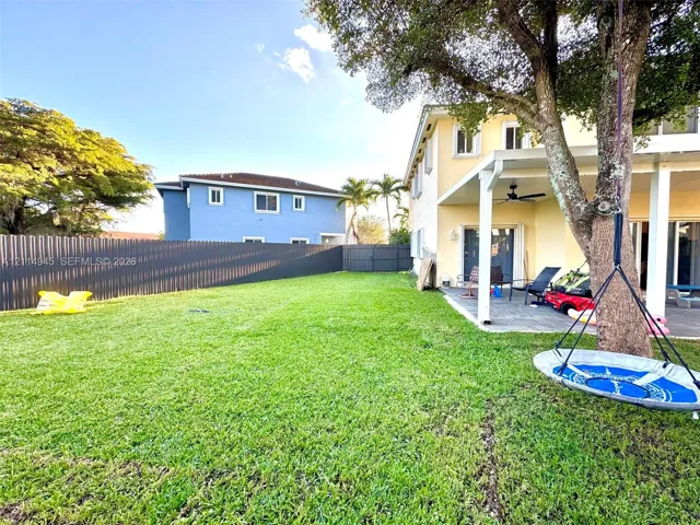 Backyard featuring a covered patio, paved hardscaping, mature tree, and full-height privacy fencing