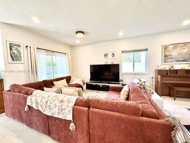 Open-concept living space featuring neutral wall paint, recessed lighting, tile flooring, and large sliding glass doors providing outdoor access