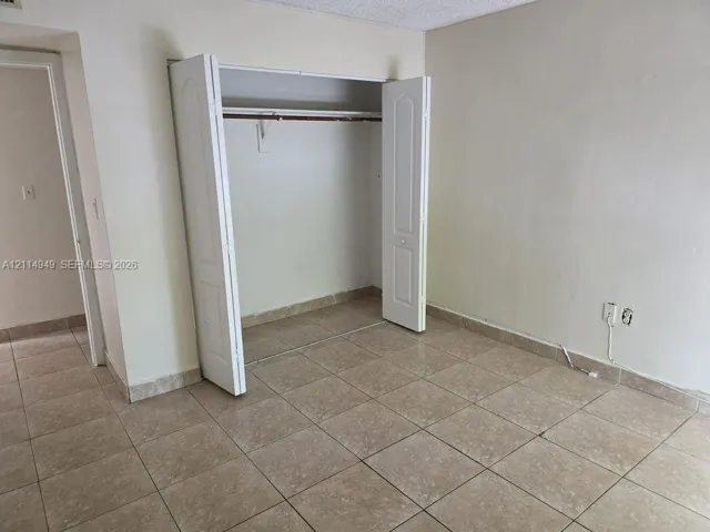 Room featuring large-format ceramic tile flooring and a built-in closet with dual-panel doors