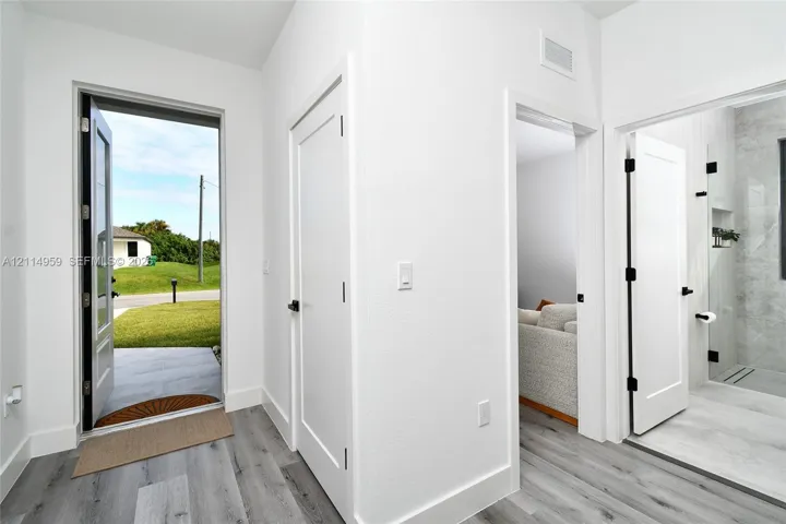 Entryway featuring wood-finish flooring, shaker-style interior doors with matte black hardware, and an exterior door with glass inlay