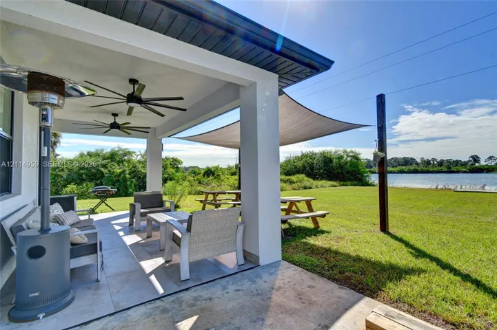 Covered patio featuring large-format tile flooring, dual ceiling fans, and structural support columns