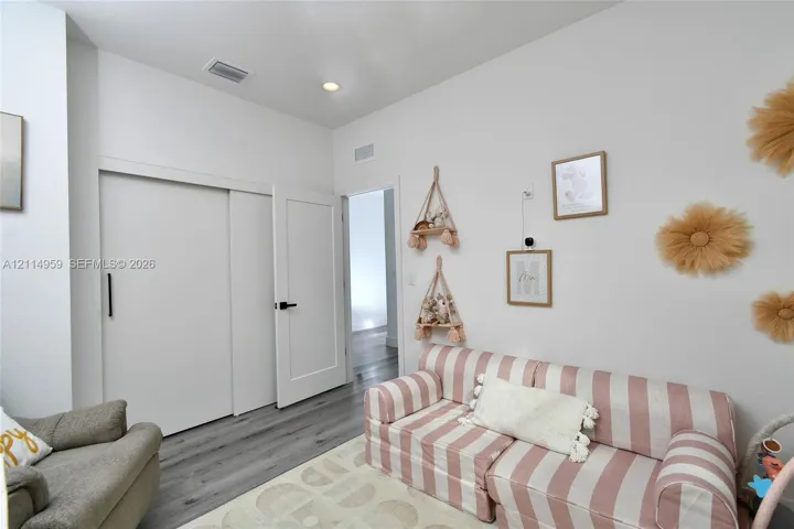 Wood-finish flooring, high ceilings, recessed lighting, and a white interior door featuring matte black hardware