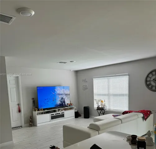 Living area featuring light-toned tile flooring, recessed lighting, and a window with horizontal blinds