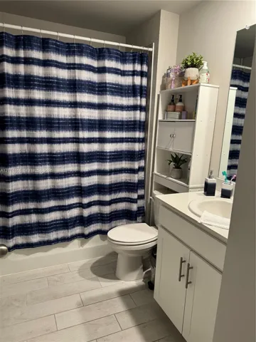 Bathroom featuring white cabinetry, an integrated sink, vertical built-in shelving, and wood-finish tile flooring