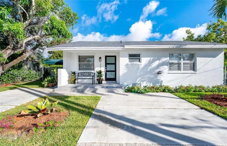 Single-story exterior featuring a crisp white facade, a modern multi-panel entry door, multi-light windows, a covered front porch, and a concrete driveway