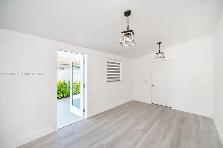 Wood-finish flooring, dual metal lantern-style pendant lights, multi-panel glass door, and adjustable dual-layer window shade