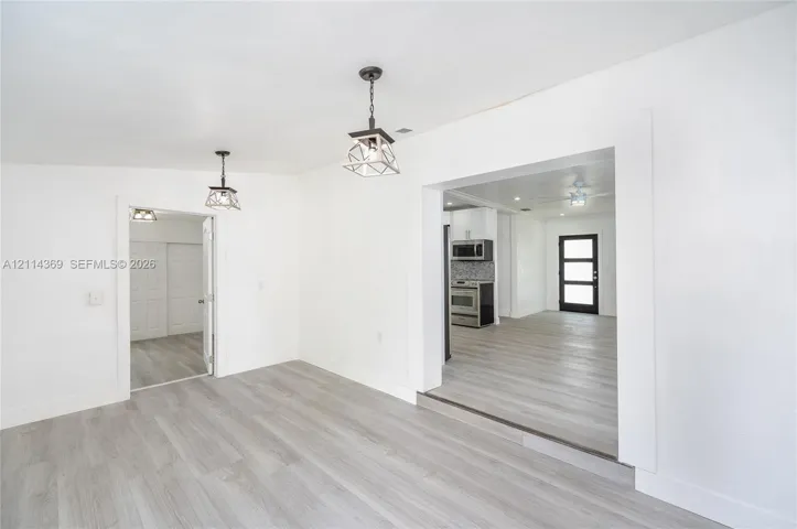 Wood-finish flooring throughout, cage-style pendant lighting, and an expansive doorway
