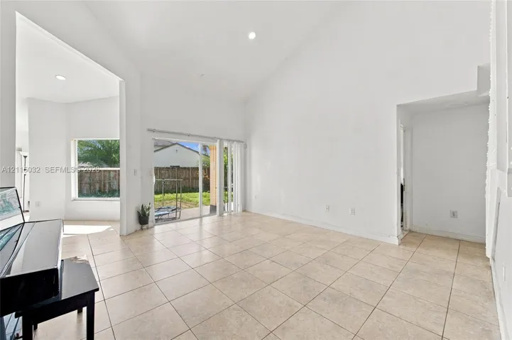 High vaulted ceilings, tile flooring, recessed lighting, and large sliding glass doors providing outdoor access