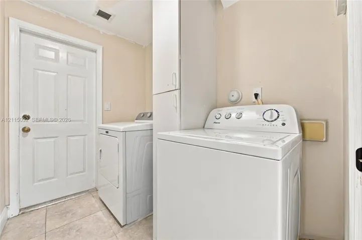 Laundry room featuring tile flooring, built-in floor-to-ceiling cabinetry, and a six-panel exterior entry door