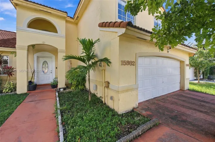 Stucco exterior featuring an arched entryway, decorative gable roofline, multi-pane windows, and a multi-car garage with a sectional door