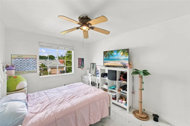 Bright room featuring large-format tile flooring, a multi-pane window, and a central ceiling fan with an integrated light fixture