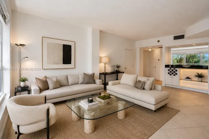 Living space featuring large-format neutral floor tile, recessed lighting, and a built-in wet bar with integrated cabinetry, wine storage, and stone-finish countertops