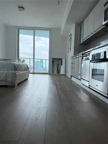 Wood-finish flooring, floor-to-ceiling glass sliding doors, stainless steel kitchen appliances, and flat-panel cabinetry