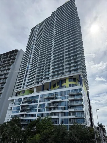 High-rise structure featuring glass curtain walls, stacked private balconies with railings, and integrated support columns
