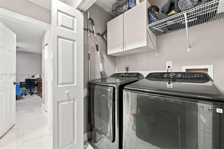 Laundry area featuring white cabinetry, wire shelving, and neutral wall tones