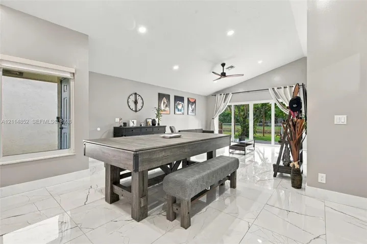 High-gloss, large-format tile flooring, vaulted ceilings, recessed lighting, ceiling fan, and multi-panel sliding glass doors
