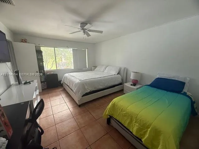 Tile flooring, white walls, built-in storage closet, and ceiling fan