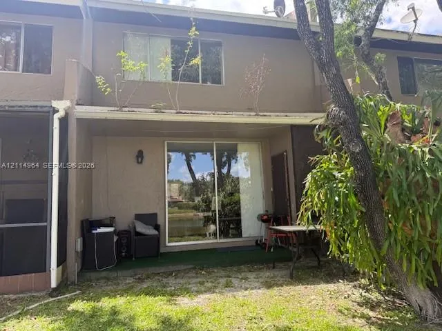 Rear exterior featuring a covered patio, sliding glass door, and stucco siding