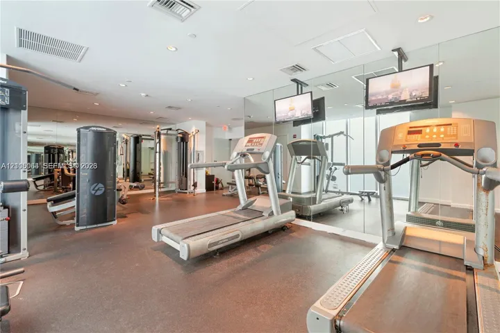Fitness center featuring mirrored walls, recessed lighting, and rubberized flooring