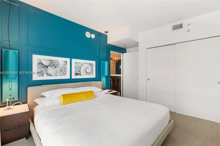 Paneled accent wall with integrated light fixtures, custom bedside cabinetry, and sliding closet doors