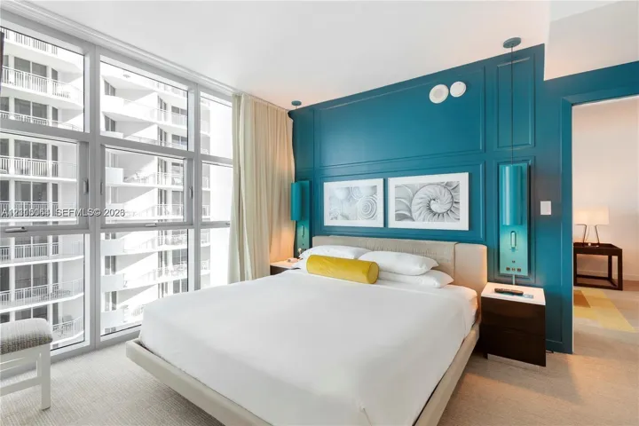 Floor-to-ceiling glass windows, custom teal paneling, and wall-mounted cylindrical light fixtures