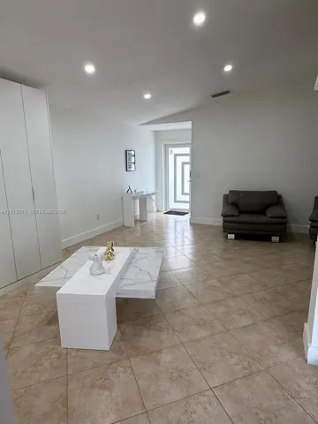 Vaulted ceiling with recessed lighting, large-format tile flooring, built-in cabinetry, and a decorative frosted glass entry door