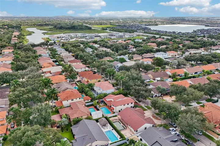 Aerial perspective featuring dense mature tree canopy, residential tiled rooflines, and proximity to regional waterways