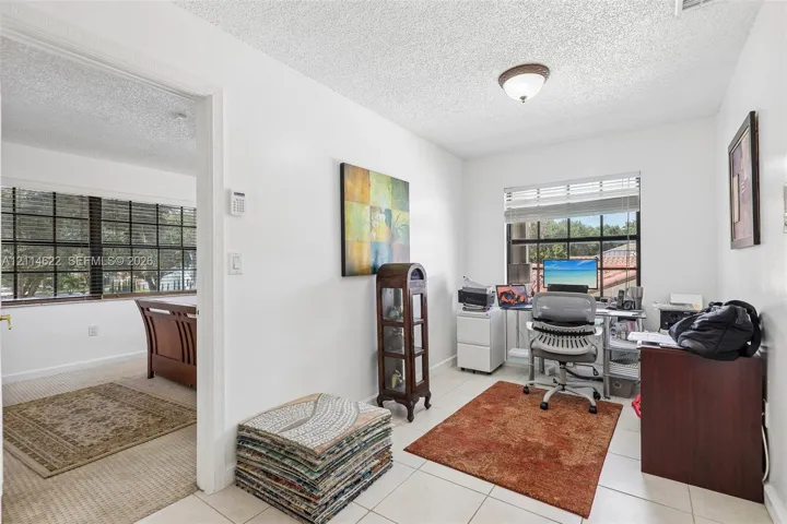 Interior space featuring large-format ceramic tile flooring, neutral wall tones, multi-pane windows with grid detailing, and a flush-mount ceiling light fixture