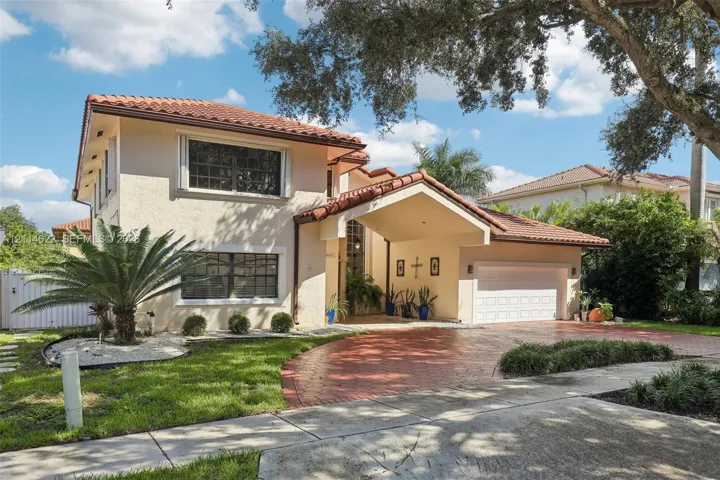 Two-story exterior featuring a tile roof, stucco finish, covered porte-cochere, and a stamped concrete driveway