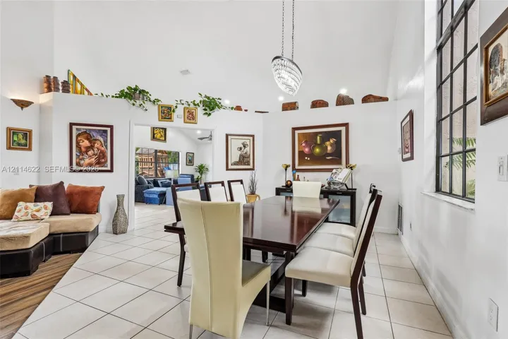 Vaulted ceilings, large-scale window with grid detailing, ceramic tile flooring, and integrated display ledge