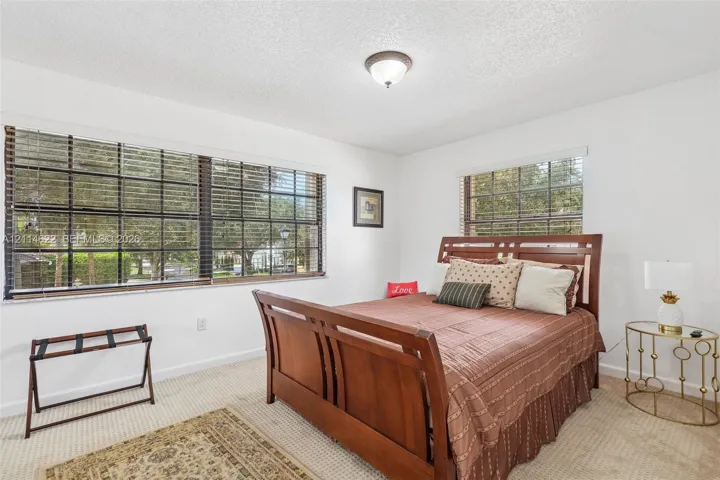 Bedroom interior featuring neutral wall-to-wall carpeting, expansive multi-pane windows, and a central ceiling-mounted light fixture