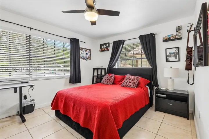 Neutral-toned tile flooring, large horizontal windows, and a central ceiling fan with integrated lighting