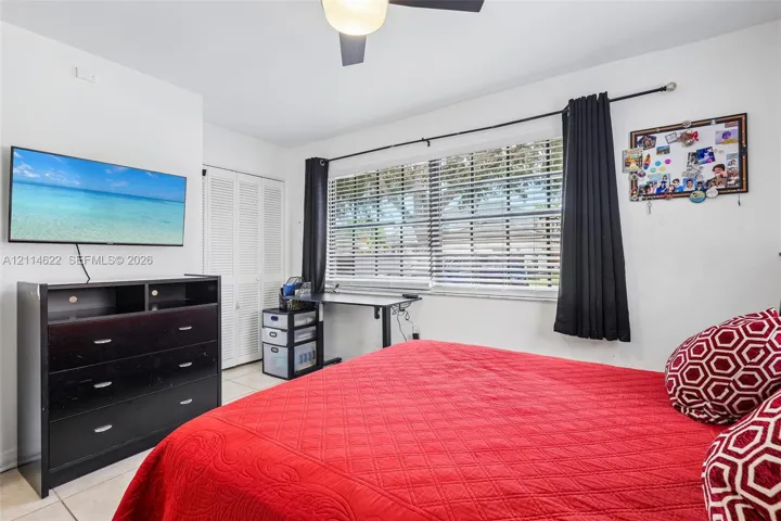 Room featuring large horizontal windows, tile flooring, louvered closet doors, and a ceiling fan with integrated lighting