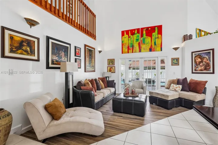 Double-height ceilings, wood-finish flooring, wooden balcony railing, and glass-paneled double doors