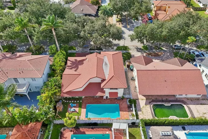 Aerial perspective featuring a tile roof, private swimming pool, brick paver patio, and mature landscaping