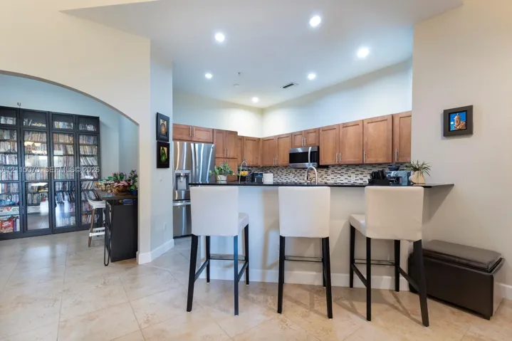 Kitchen featuring wood-finish cabinetry, dark solid-surface countertops, stainless steel appliances, recessed lighting, and tile flooring
