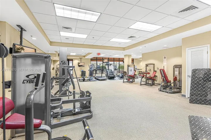 Fitness center featuring a drop ceiling, recessed grid lighting, wall-to-wall carpeting, and floor-to-ceiling windows