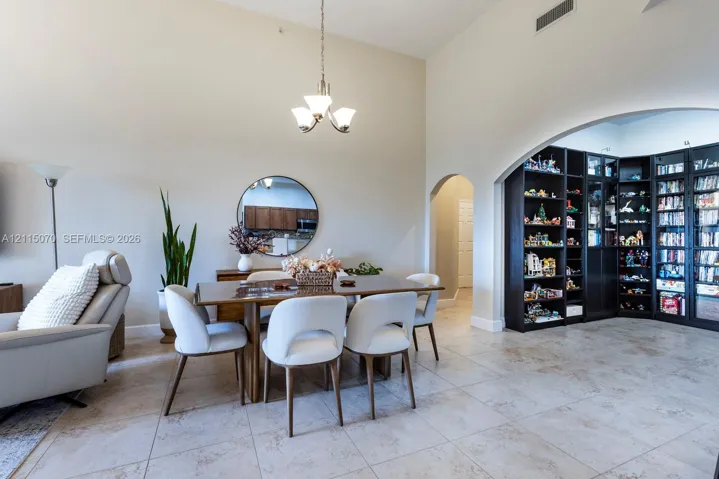 Vaulted ceilings, large-format tile flooring, built-in floor-to-ceiling shelving, arched architectural detailing, and a multi-arm pendant light fixture