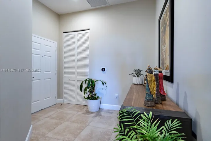 Neutral-toned interior featuring tiled flooring, a six-panel door, and a white louvered-style closet door