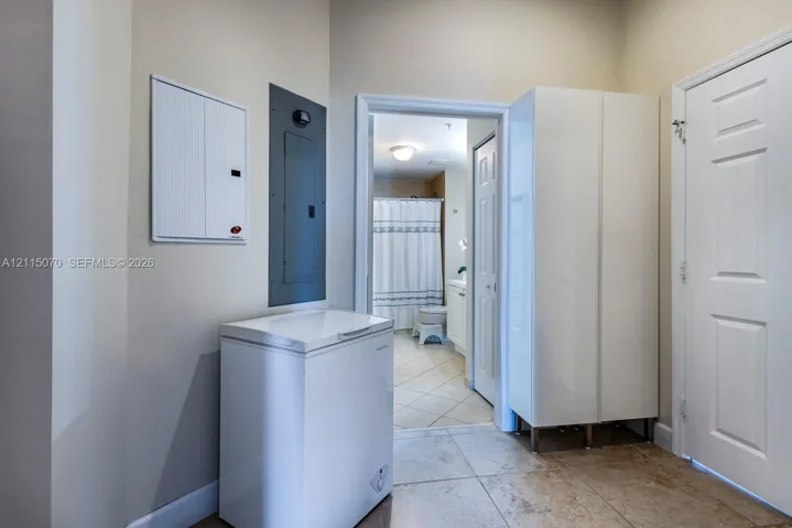Service area featuring large-format ceramic tile flooring, tall built-in white cabinetry, and wall-mounted electrical panel