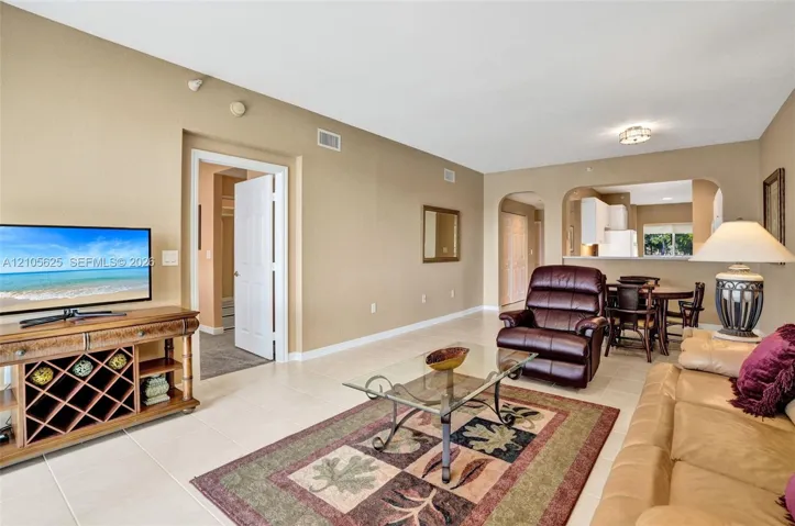 Open-concept living space featuring large-format ceramic tile flooring, neutral wall tones, arched wall openings, and recessed ceiling lighting