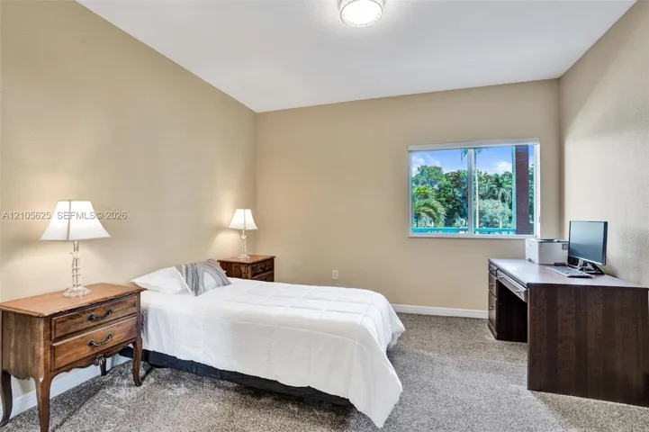 Neutral-toned interior featuring high ceilings, wall-to-wall carpeting, and a large window with exterior greenery