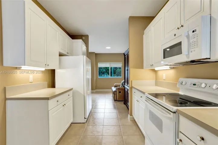 Kitchen featuring white cabinetry, solid surface countertops, under-cabinet lighting, and tile flooring