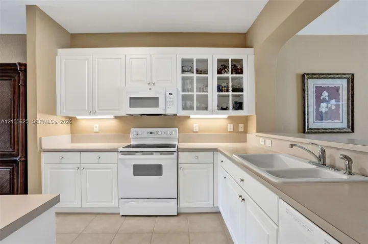 Kitchen featuring white cabinetry, integrated glass-front display cabinets, solid surface countertops, an electric range, and a double-basin sink